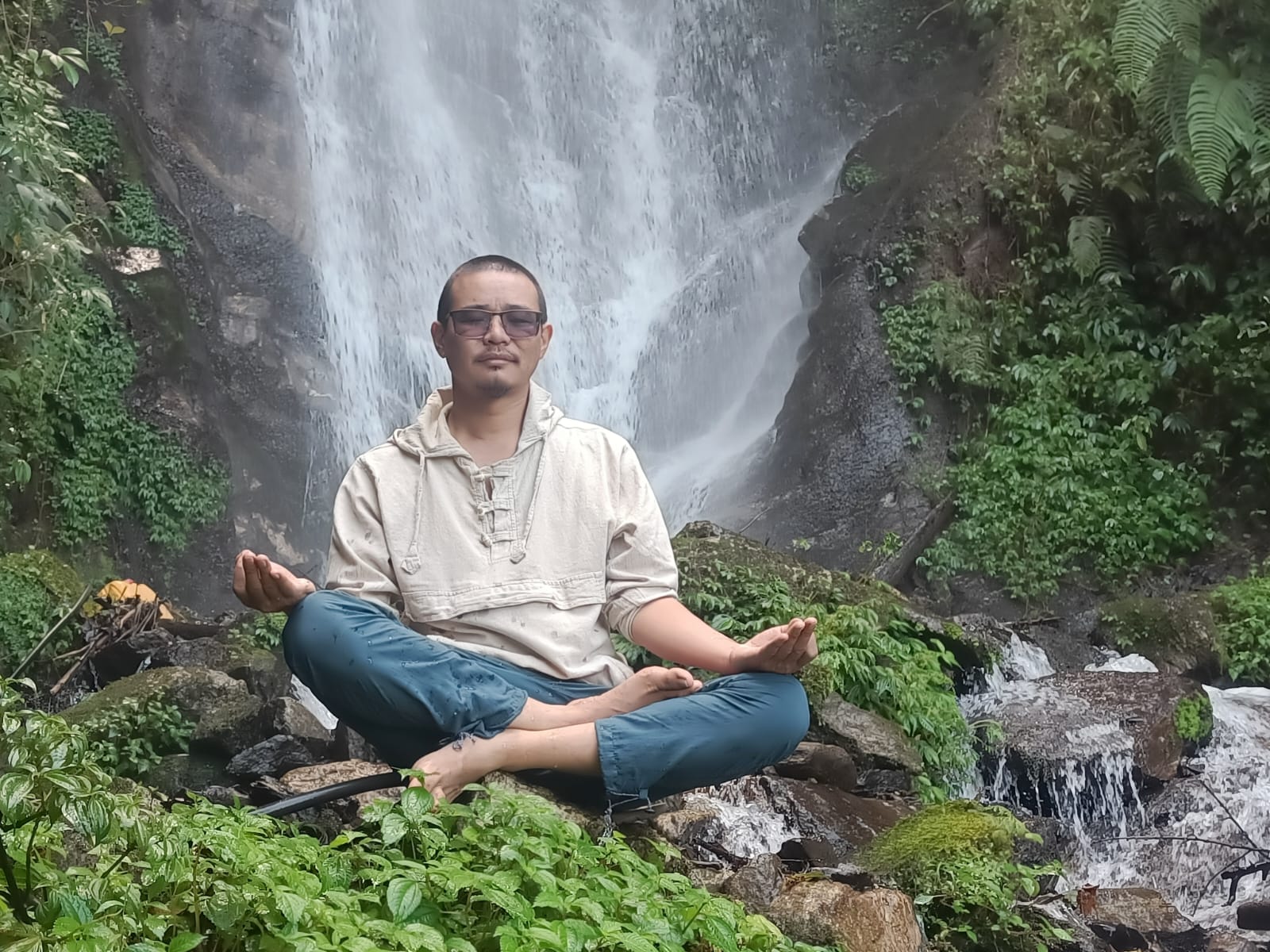 Seated meditation beside a forest waterfall in the hills of Nepal