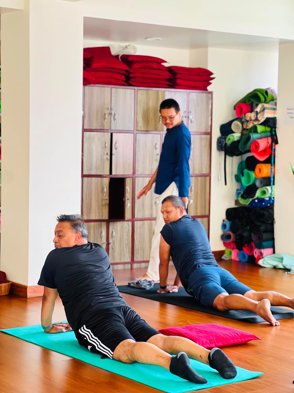 Yoga teacher adjusting students' postures in a class at Yogmandu, Kathmandu