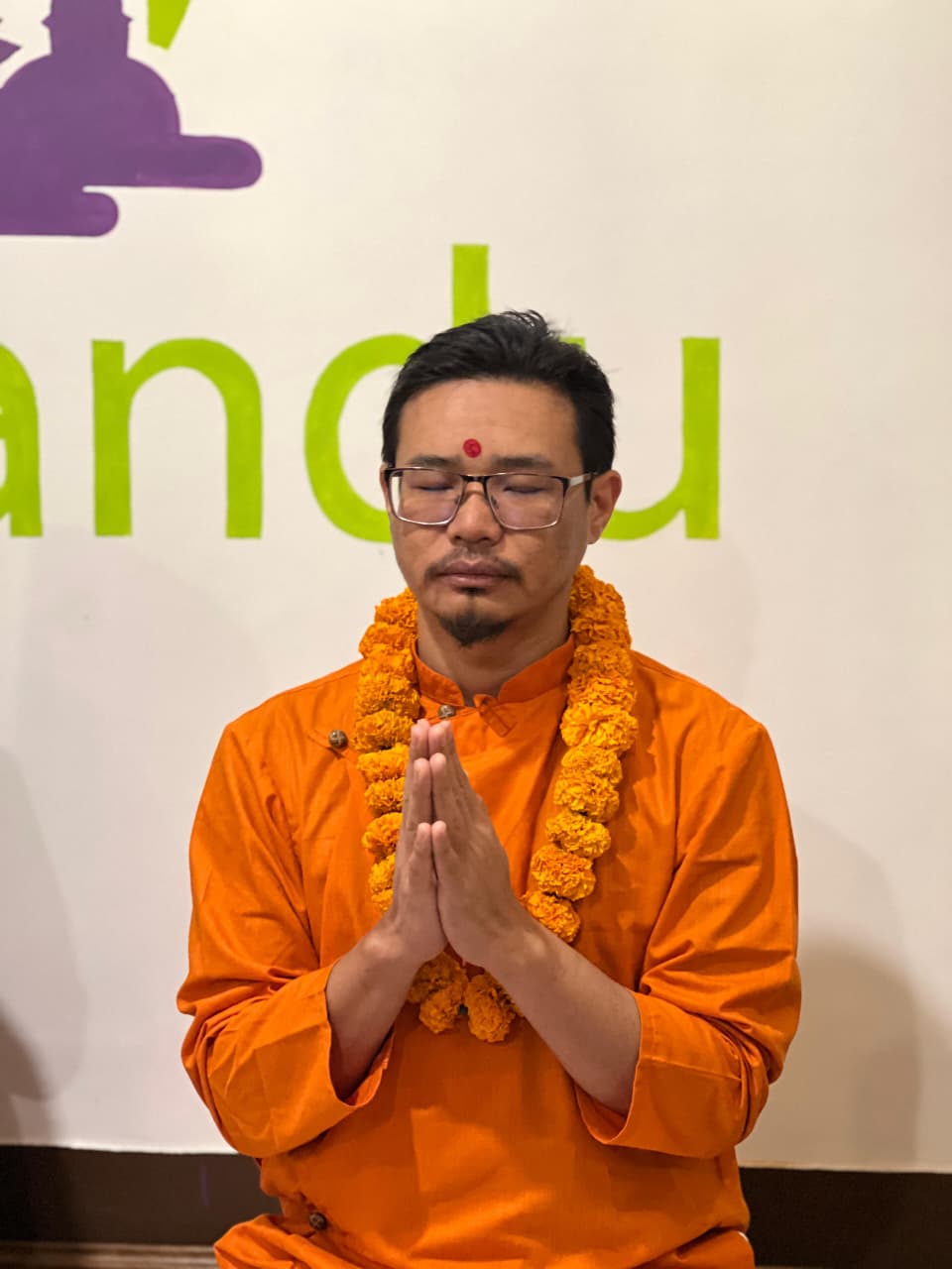 Yoga teacher in saffron with namaste mudra at Yogmandu studio, Kathmandu